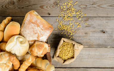 Vari tipi di pane e chicchi su piano di legno 