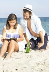 Fototapeta premium Couple sitting in the sand leaning on each other.