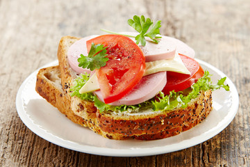 breakfast sandwich with sliced sausage and tomato
