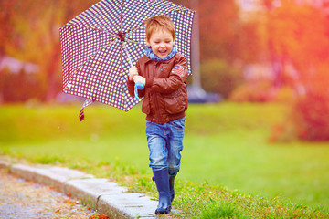 happy boy running under an autumn rain