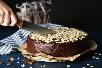 Female cutting chocolate cake with almond,