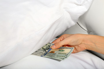 Woman hiding money under pillow at home