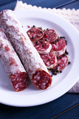 French salami on plate on napkin on dark blue wooden background