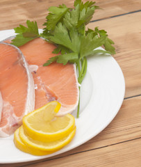 raw salmon steak on white dish over wooden table