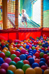 Cute Child playing at Ball Pit. Colorful scene.