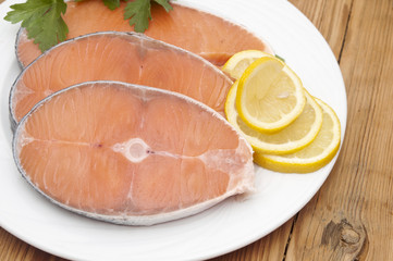 dish for baking with slices of salmon over wooden table