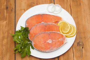 dish for baking with slices of salmon over wooden table