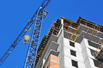 Crane lifting concrete mixer container against blue sky