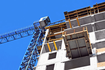 Crane and building construction site against blue sky