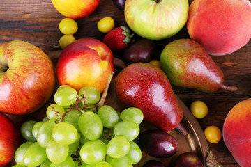 Different berries and fruits on tray on wooden table close-up