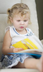 Fototapeta premium Blonde Haired Blue Eyed Little Girl Reading Her Book