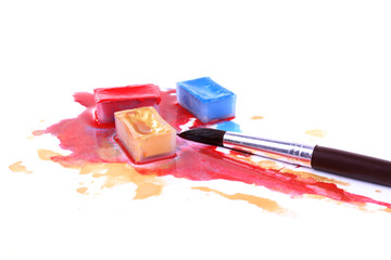 Watercolor paint cube with brush and spilled paint isolated