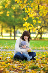 Young mother with her little baby in the autumn park