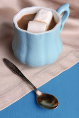 Cup of coffee with marshmallow and napkin on wooden table