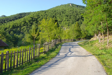 Fototapeta na wymiar Rural Road With Wooden Fence In Serbia