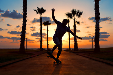 man riding on skateboard near the ocean in sunset