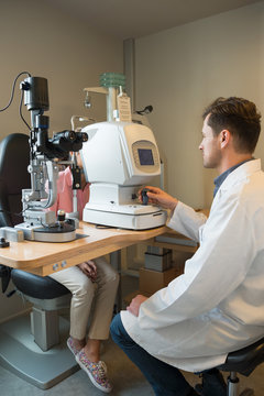 Male optometrist examining woman's eyes