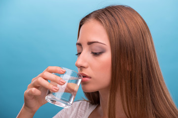 Portrait of young beautiful girl drinking clean water from a gla