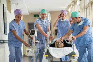Medical professionals pushing patient on gurney in a hospital