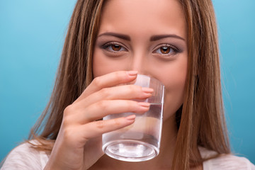 Portrait of young beautiful girl drinking clean water from a gla