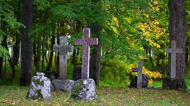 Old stone crosses on graves with autumn trees around