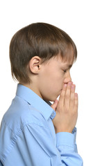 Young sad praying boy standing isolated