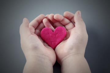 Child's hands holding the cracked pink heart