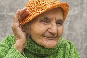 Elderly woman holding hand close to an ear.