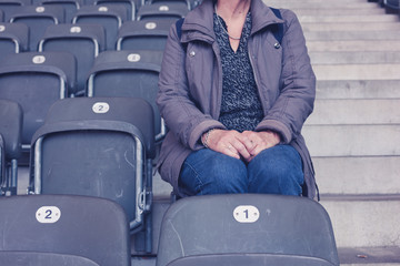Elderly woman sitting on bleachers in empty stadium