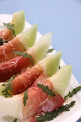Ripe melon with ham, parmesan on white plate