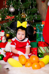Fototapeta na wymiar happy little girl in a New Year's suit near a Christmas tree
