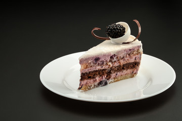 Cake triangular shape with black berries on a white plate
