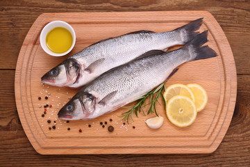 Two fresh moronidae fish on cutting board with ingredients
