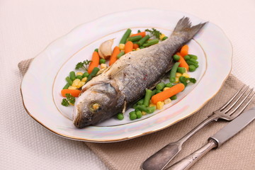 Grilled whole sea bass with vegetables and lemon