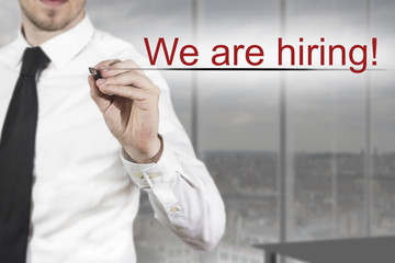 businessman writing we are hiring in the air
