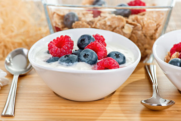 Bowl with berries and yoghurt on a bamboo mat close up