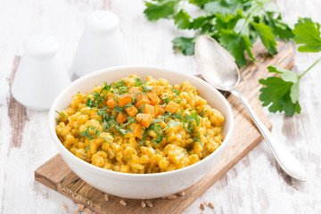 barley porridge with pumpkin and greens in a bowl, horizontal