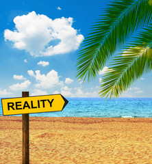 Tropical beach and direction board saying REALITY