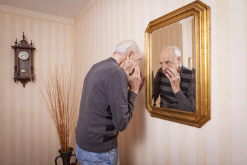 elder man looking at himself at the mirror