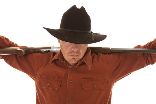cowboy with arms on gun over shoulders head down