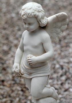 little angel kneeling with garlands of flowers in hands