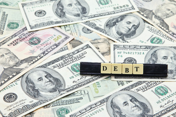 Word debt on pile of US dollar banknotes