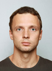 Fototapeta premium Young Caucasian man closeup portrait. Headshot on gray