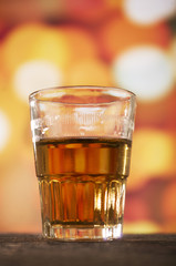 glass of rum whiskey over defocused lights background