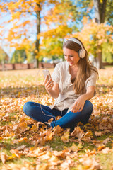 Young woman listening to music in an autumn park