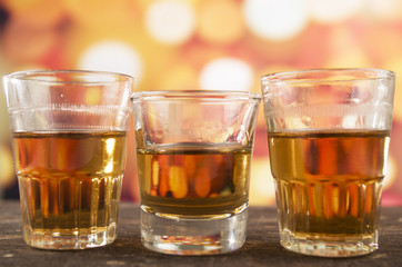 glass of rum whiskey over defocused lights background