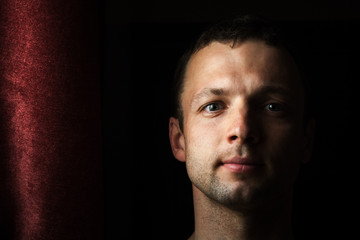 Young Caucasian man close up portrait with curtain