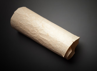 Old yellow crumpled paper roll on black table