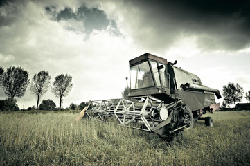 Old broken combine abandoned in the field during work