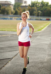 Smiling young woman jogging, training run outdoors